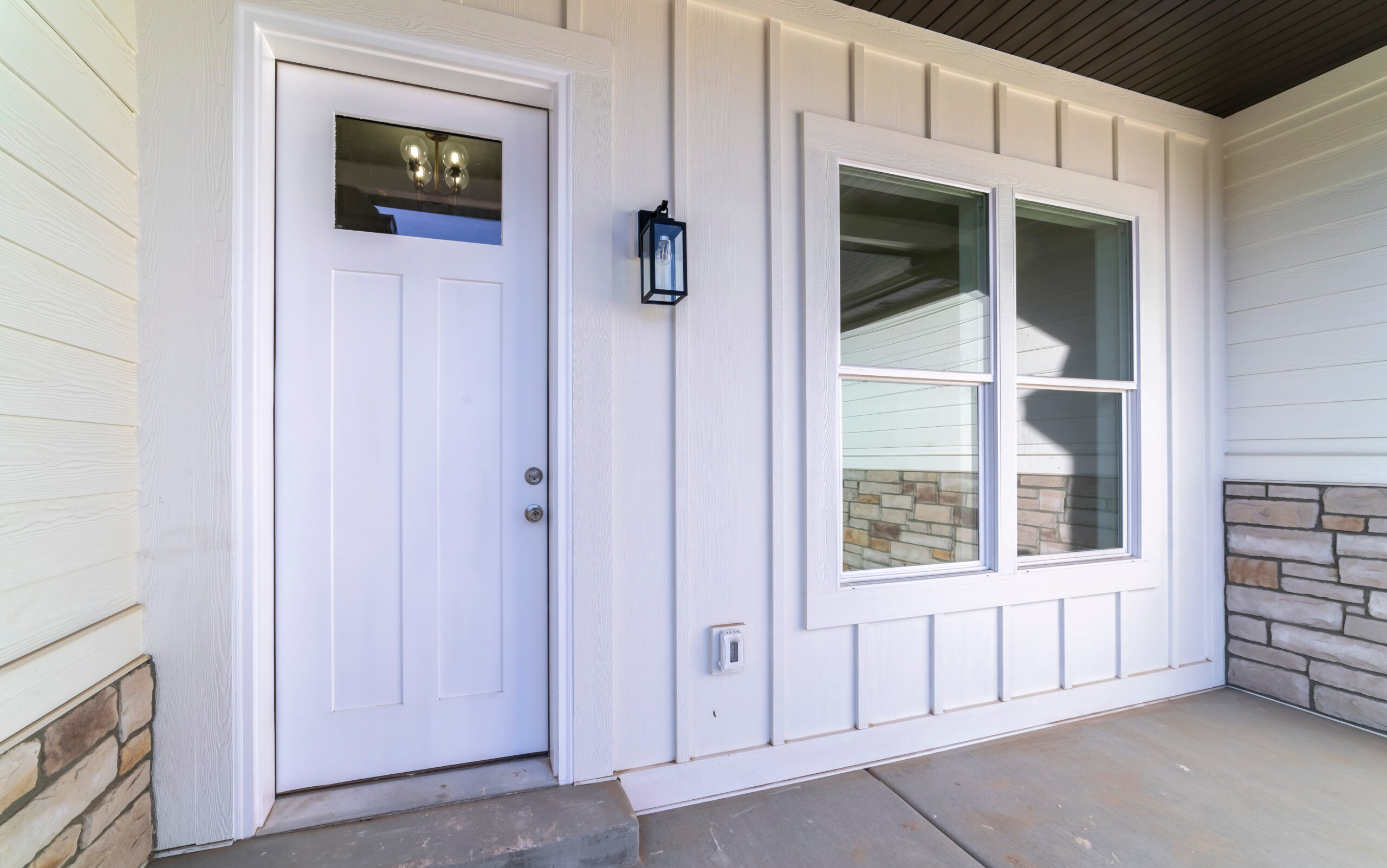 Large square window alongside a white door on a covered front porch of an urban house