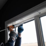 Gloved hands are sealing the top of a white window frame with a caulking gun against a dark interior wall. Glacier_Glass_Regina Glacier_Glass_Regina Glacier_Glass_Regina Glacier_Glass_Regina Glacier_Glass_Regina Glacier_Glass_Regina Glacier_Glass_Regina Glacier_Glass_Regina Glacier_Glass_Regina