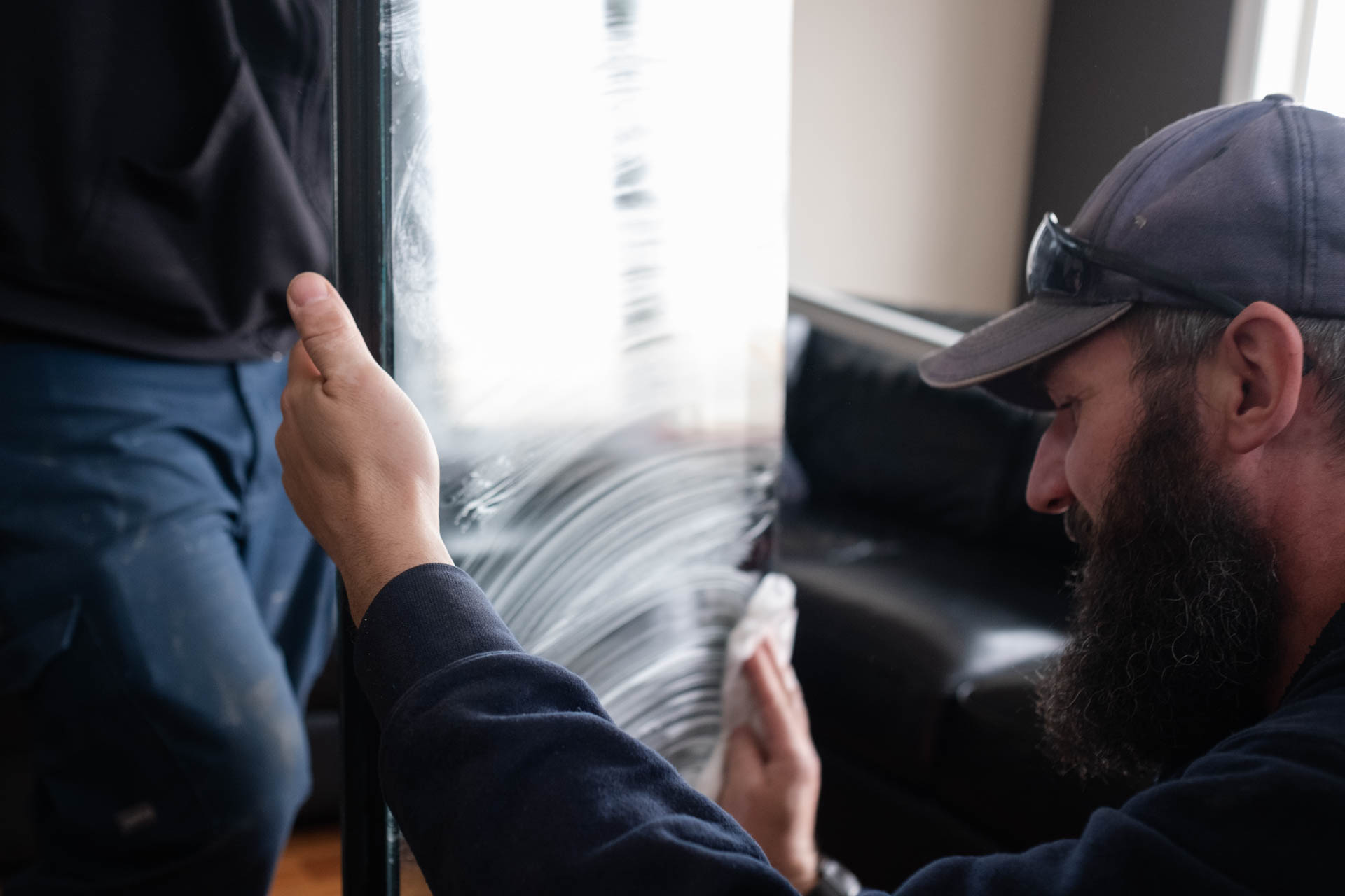 Glacier Glass employee carefully wiping and inspecting a window pane for imperfections before installation