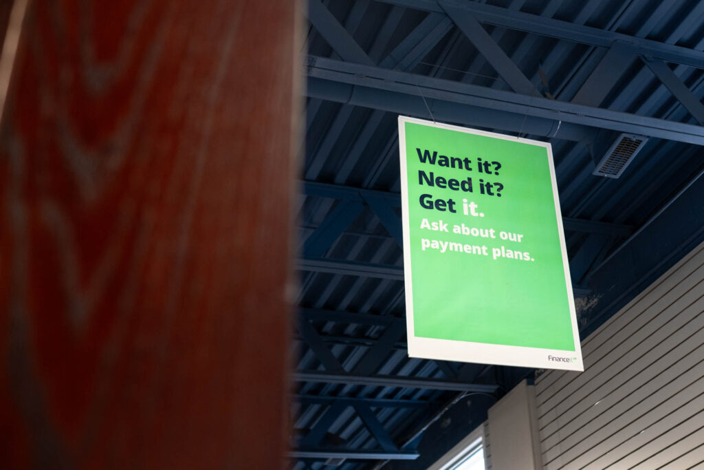 A Green sign in Glacier Glasses office hanging from a roof that says Want it? Need it? Get it. Ask about our payment plans