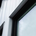 A modern building with white vertical siding features a large dark framed window reflecting a bright sky, alongside partially visible black block letters of a sign. Glacier_Glass_Regina Glacier_Glass_Regina Glacier_Glass_Regina Glacier_Glass_Regina Glacier_Glass_Regina Glacier_Glass_Regina Glacier_Glass_Regina Glacier_Glass_Regina Glacier_Glass_Regina Glacier_Glass_Regina Glacier_Glass_Regina Glacier_Glass_Regina Glacier_Glass_Regina