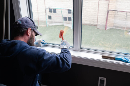 Glacier Glass Employee Replacing a window, with an orange mallet in hand.