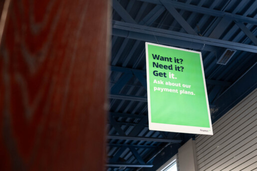 A Green sign in Glacier Glasses office hanging from a roof that says Want it? Need it? Get it. Ask about our payment plans