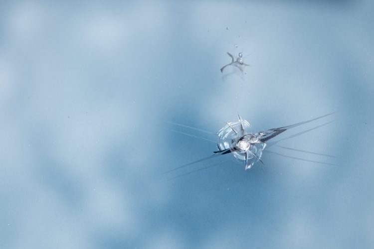 Windshield has cracks from the impact of stone chips while driving.